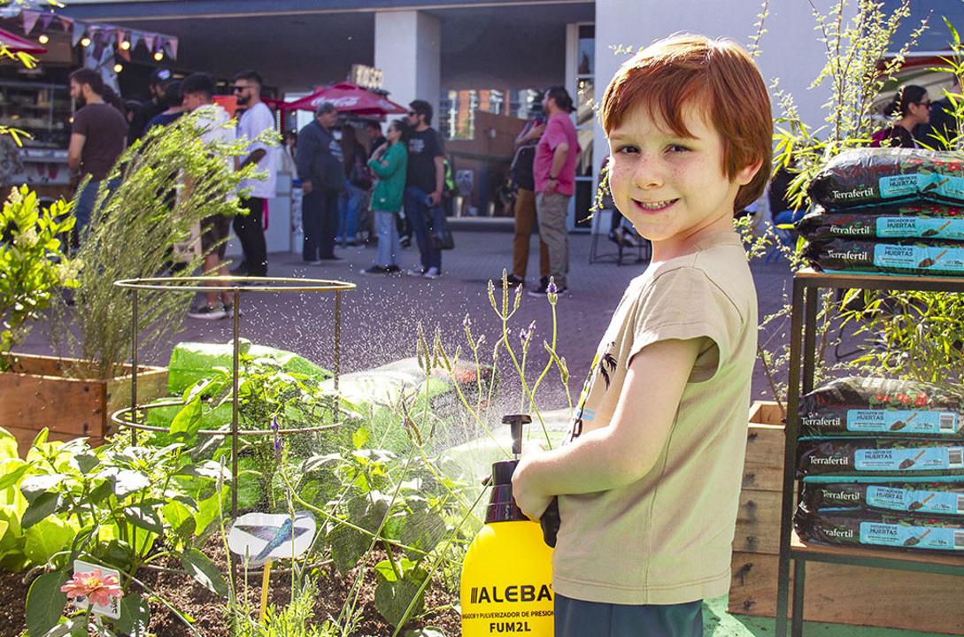 Niños y niñas explorando una huerta interactiva en Expo Cannabis con frutas, verduras y aromáticas